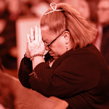 Hispanic woman praying during church service